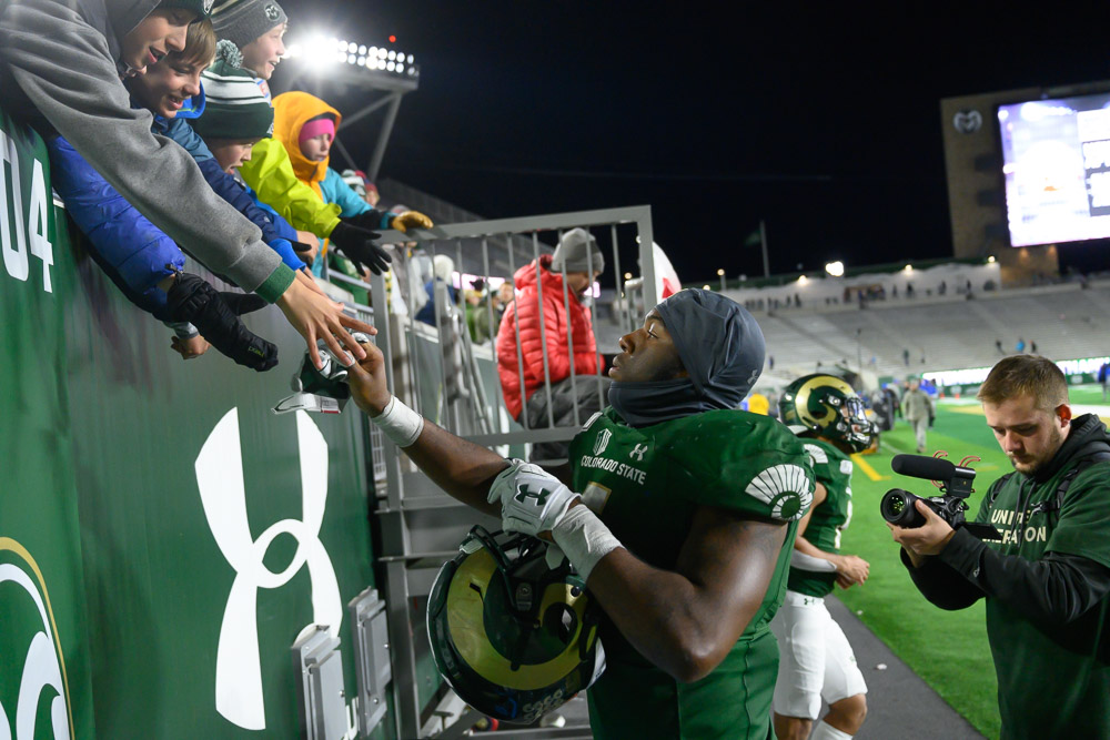 A CSU football player handing something to a fan in the stands